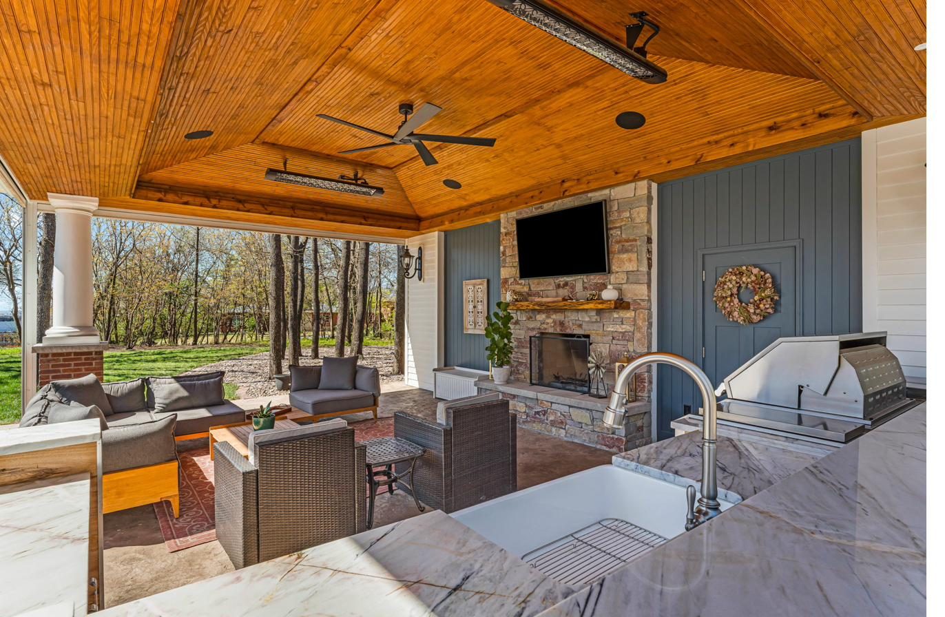 Naismith House lanai interior — outdoor kitchen, stone fireplace, cedar ceiling